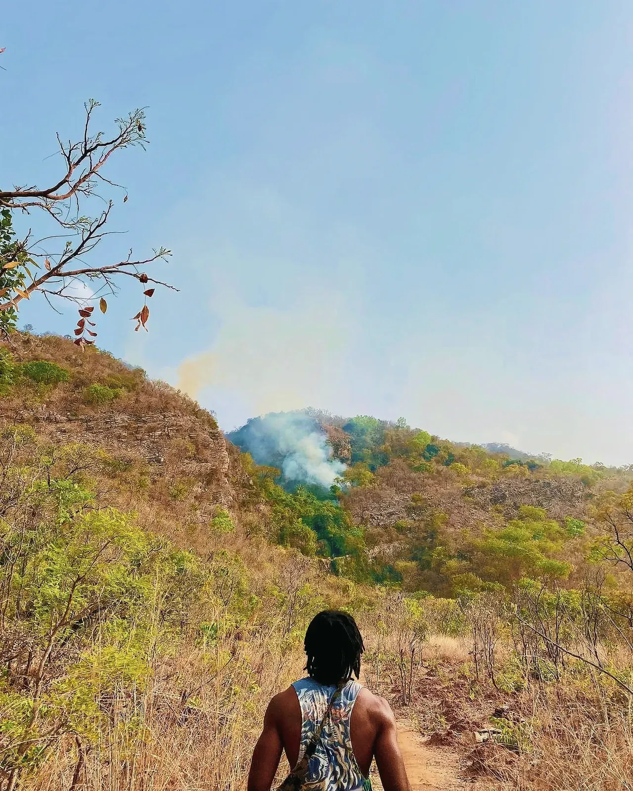 A hiker observing a forest fire in the distance in the Region de la kara