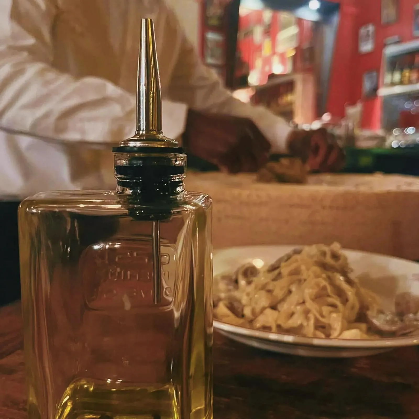 Cozy indoor dining scene with a glass bottle of Grana Padano cheese at The Cousins Trattoria